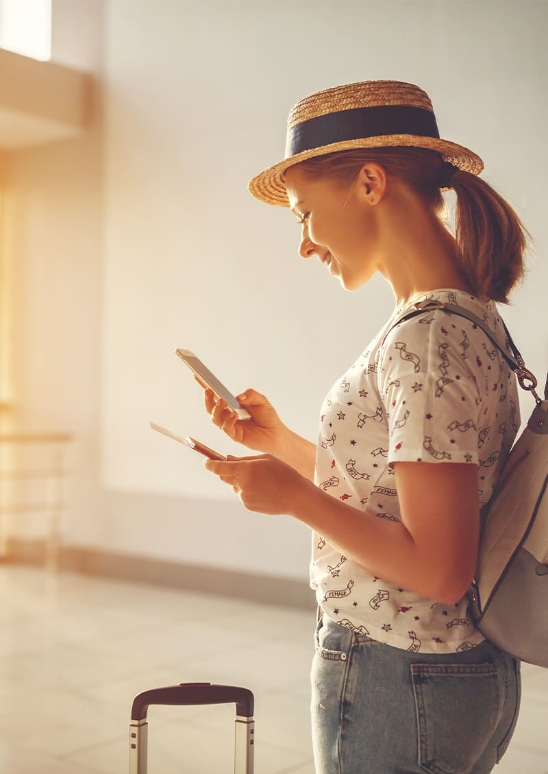 jeune femme avec un chapeau un telephone un sac a dos et une valise